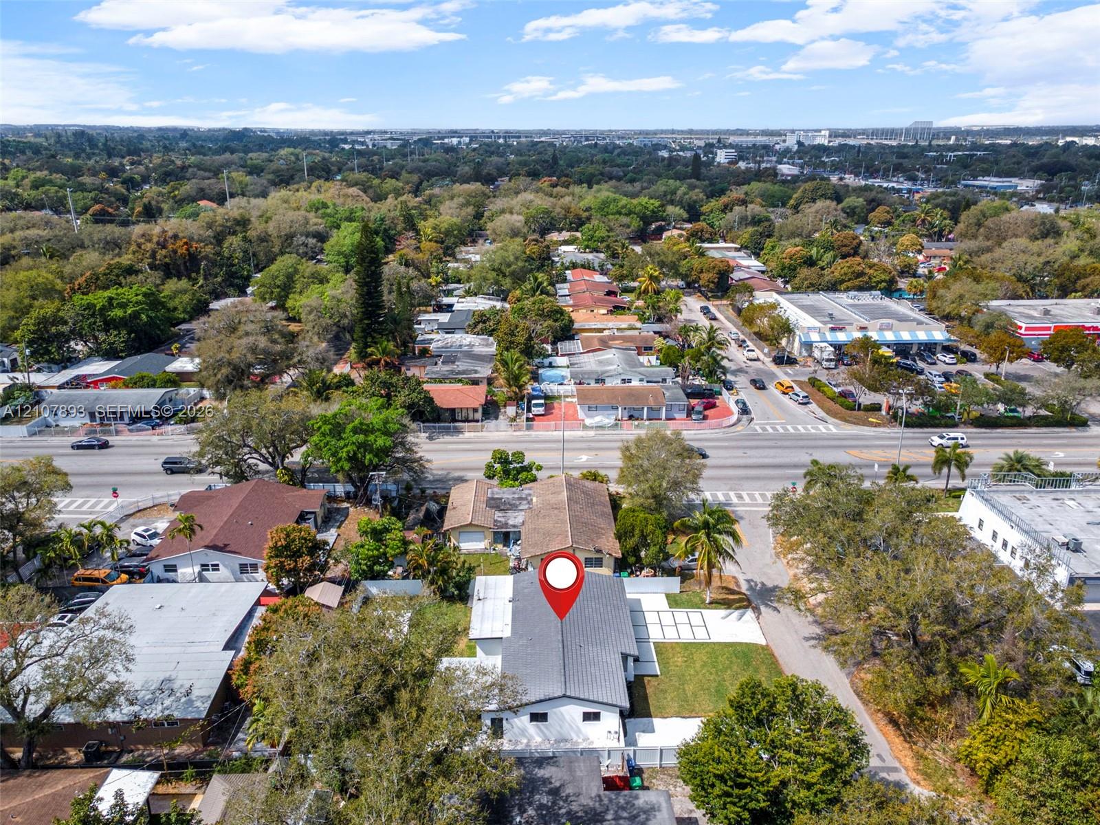 Aerial perspective featuring a multi-pitched shingle roof, white exterior finish, and a paved grid-patterned driveway