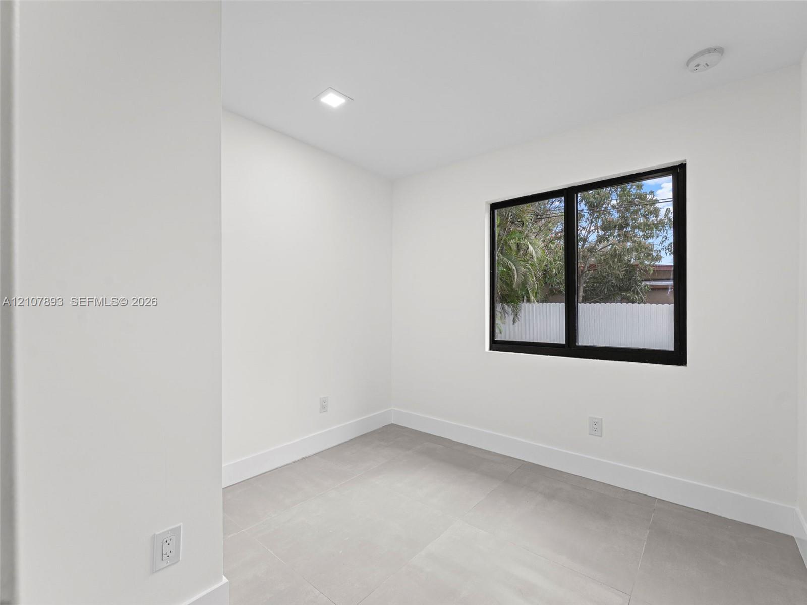Neutral-toned tile flooring, recessed ceiling lighting, and a window with a black frame