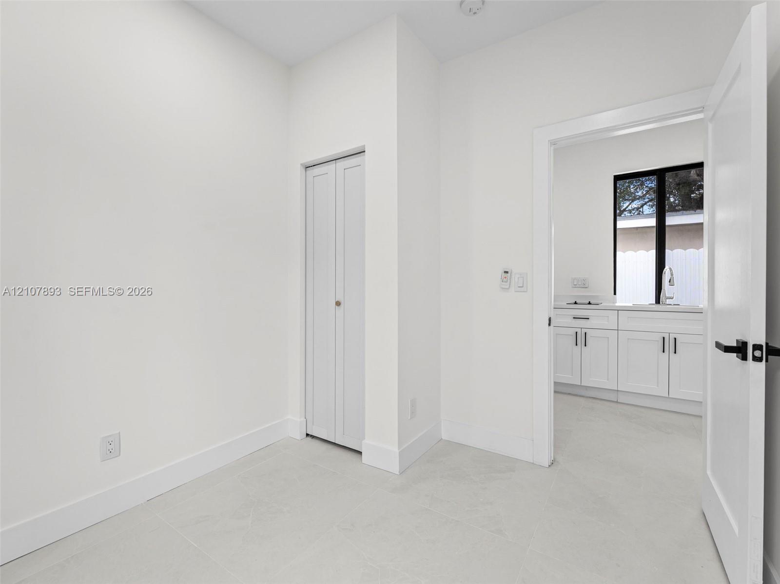 Neutral-toned tile flooring, bi-fold closet doors, and interior doors featuring matte black hardware