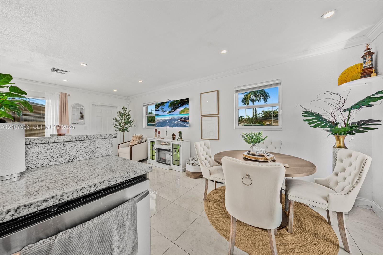 Open-concept kitchen featuring speckled stone countertops, polished tile flooring, recessed ceiling lighting, and crown molding