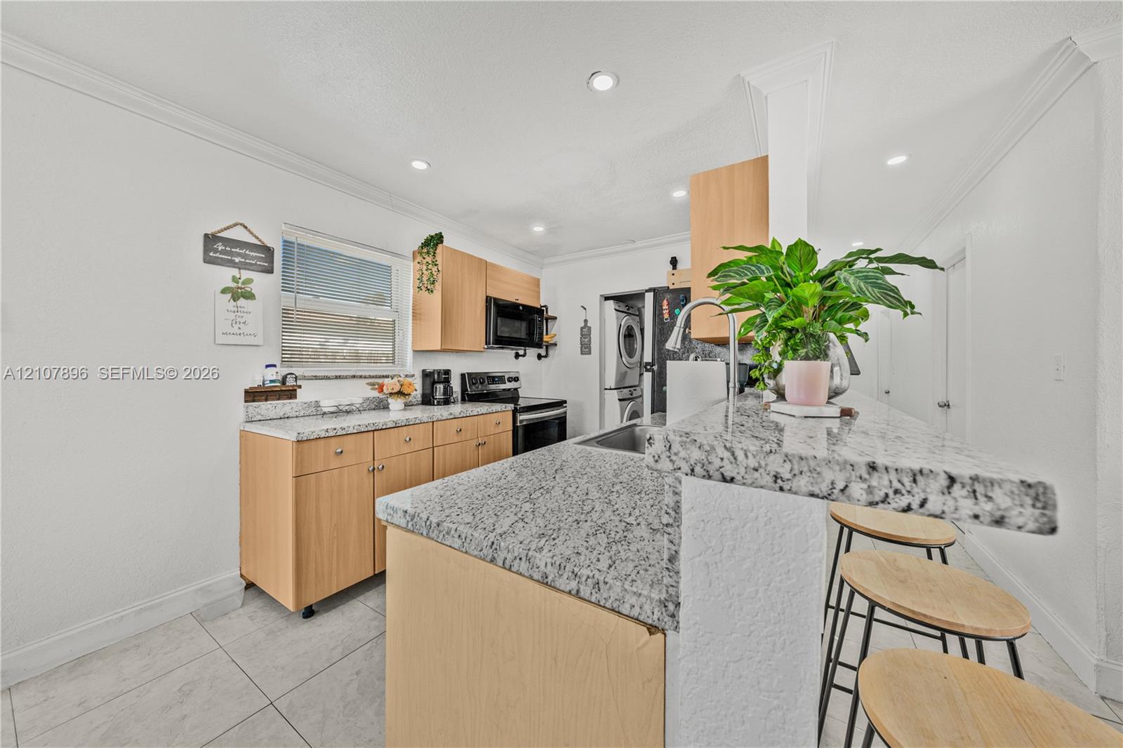Kitchen featuring natural wood-finish cabinetry, stone-style countertops, recessed ceiling lighting, tile flooring, and a breakfast bar