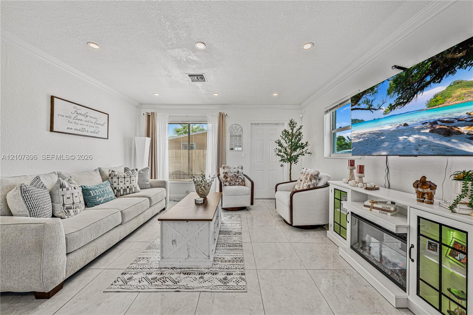 Living area featuring large-format tile flooring, recessed lighting, crown molding, and a built-in media console with an integrated fireplace