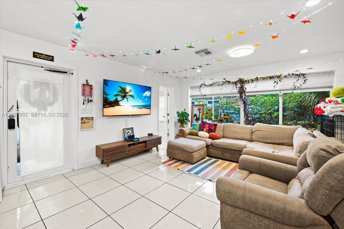 Spacious room featuring large-format ceramic tile flooring, neutral wall finishes, flush-mount LED ceiling lighting, and expansive windows with natural light exposure