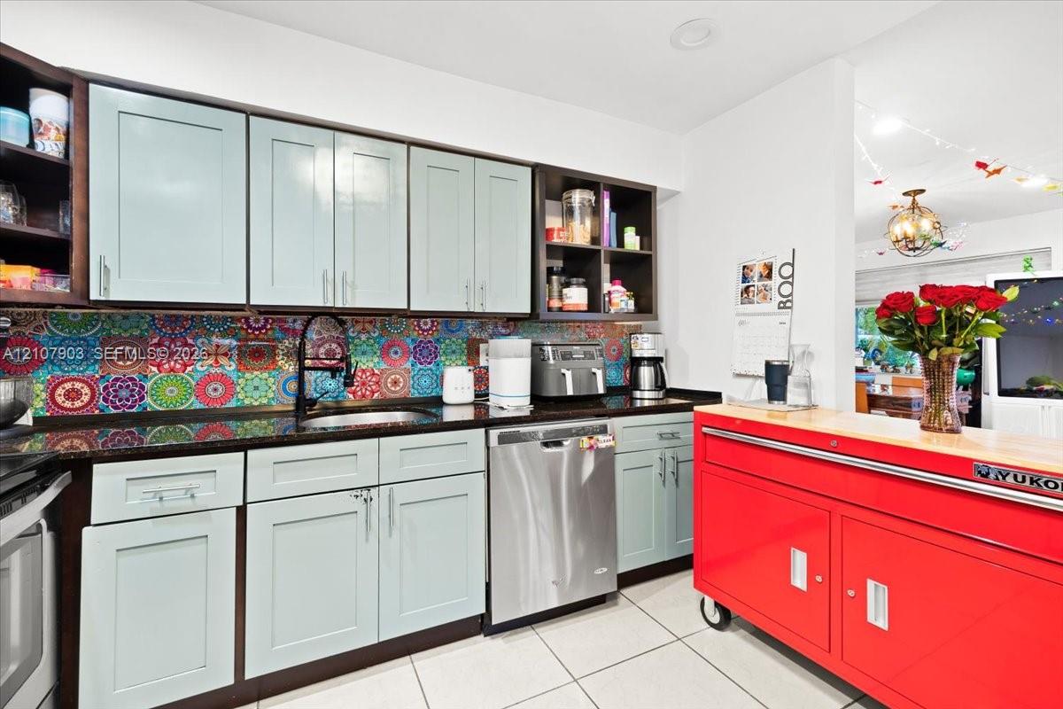 Kitchen featuring light-toned cabinetry, patterned mosaic tile backsplash, dark solid-surface countertops, stainless steel dishwasher, and recessed lighting