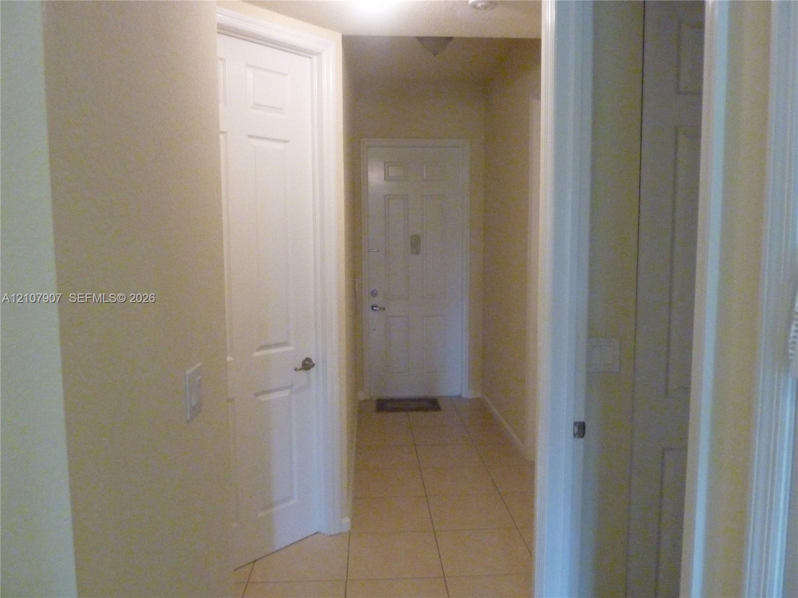 Entryway featuring neutral tile flooring, multiple six-panel interior doors, and a solid-core exterior entry door