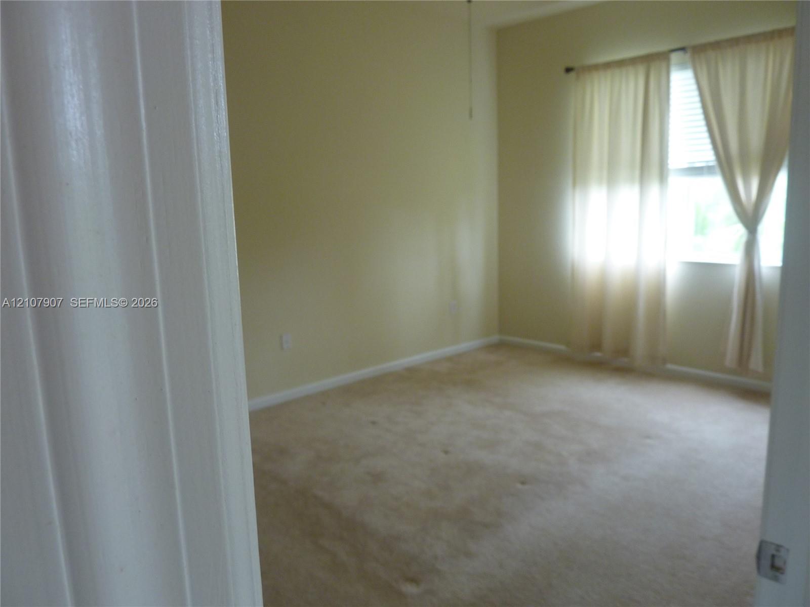 Interior room featuring carpeting, high ceilings, and a window with blinds