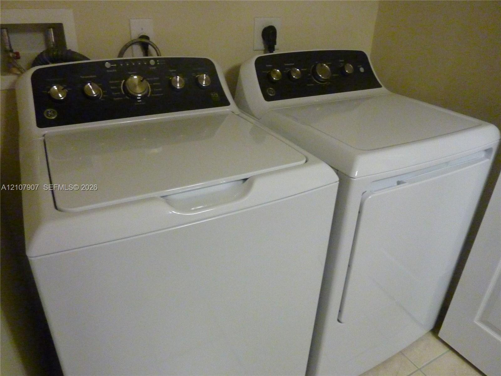 Top-load white washing machine and matching dryer featuring high-contrast black control panels with brushed metallic dials