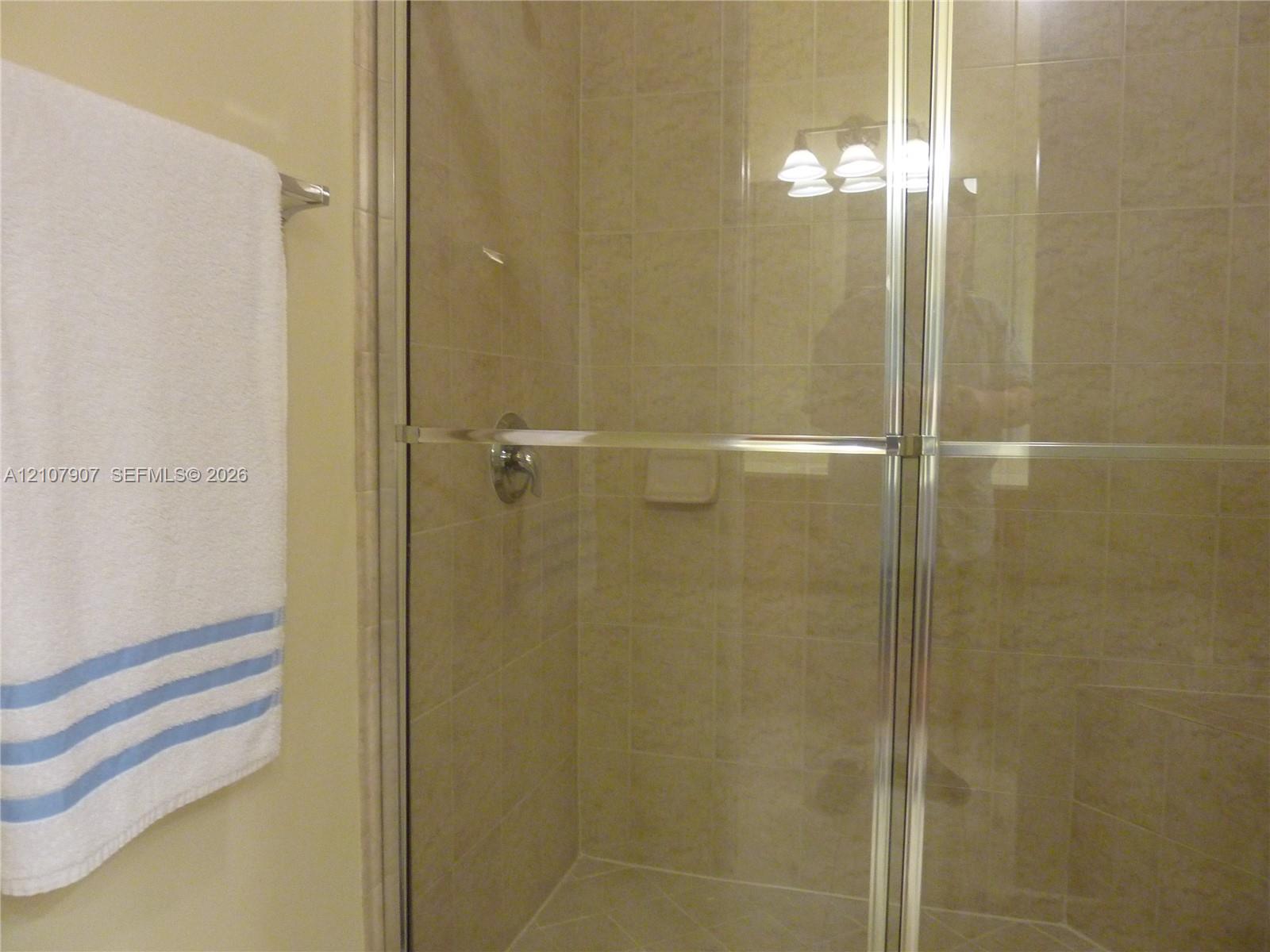 Shower enclosure featuring neutral-toned wall tile, a metal-framed glass door, and integrated tile soap niche