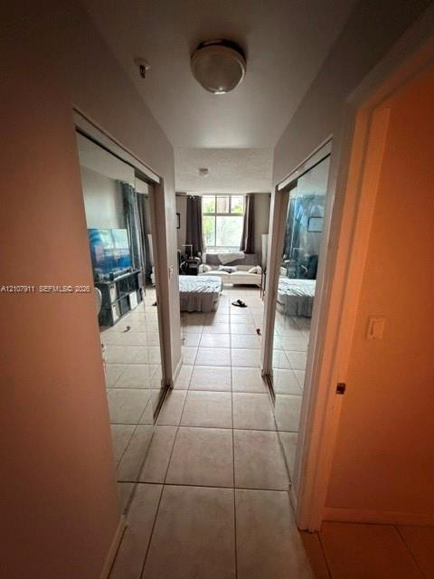 Hallway featuring light-toned tile flooring and dual mirrored sliding-door closets