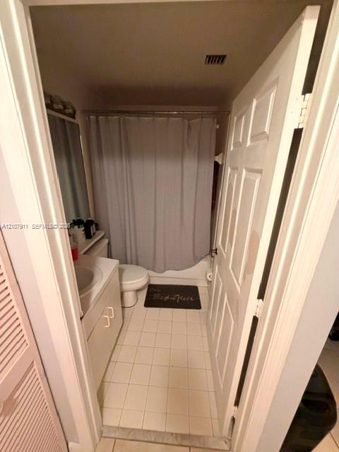 Bathroom featuring tile flooring, white cabinetry, integrated sink, and a tub-shower combination with a shower rod