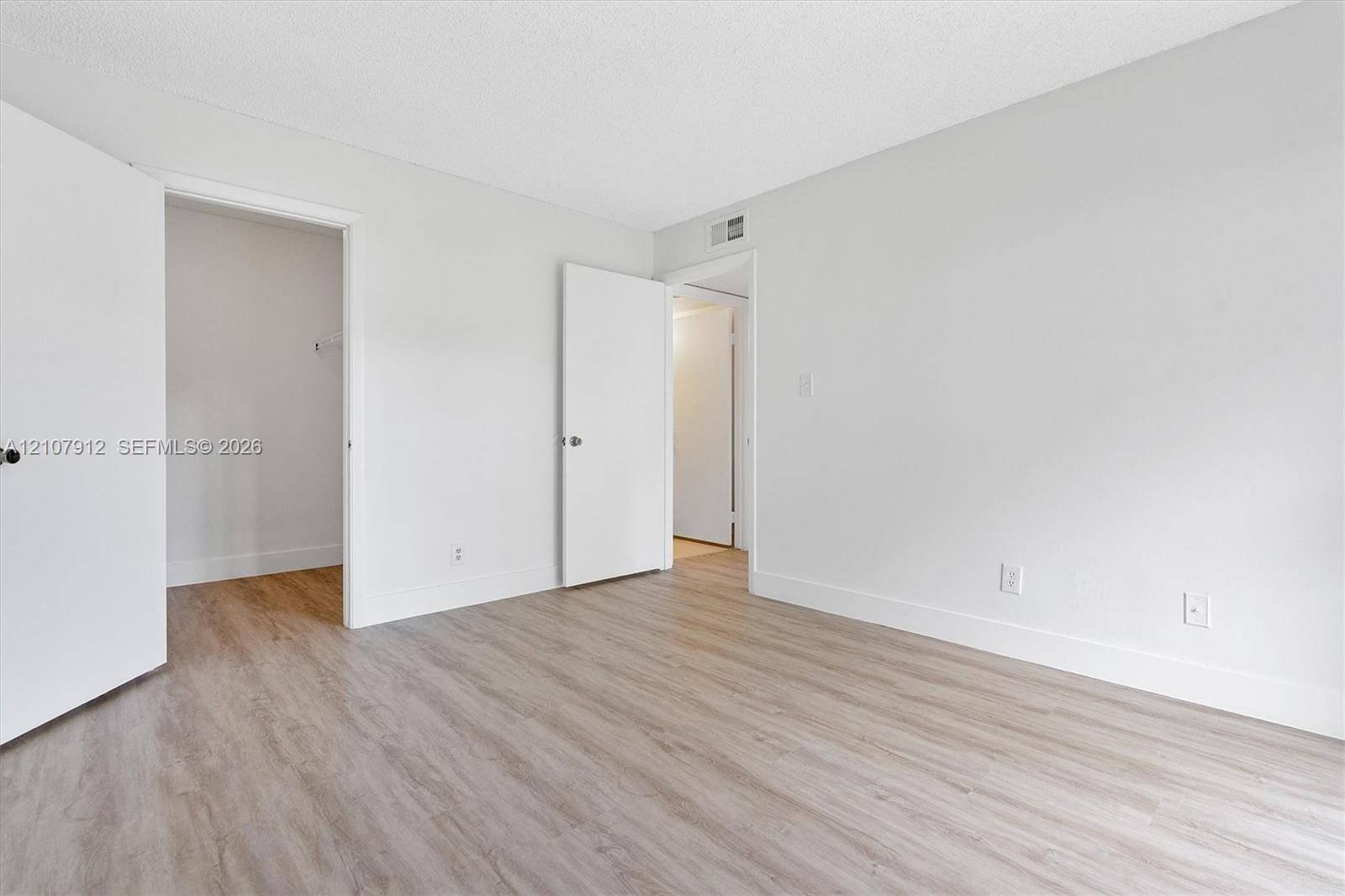 Neutral-toned walls, wood-finish flooring, and multiple interior doors
