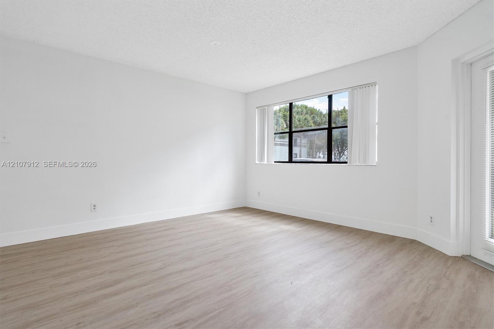 Interior space featuring wood-finish flooring, a large picture window with black frames, and a glass-paneled door