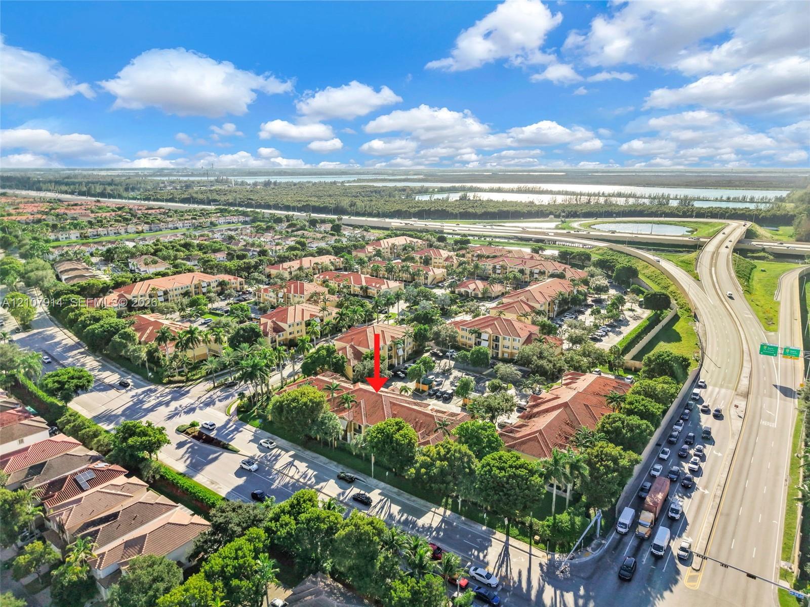 Aerial view of multi-story residential complex featuring red tile roofs, mature trees, and landscaped grounds