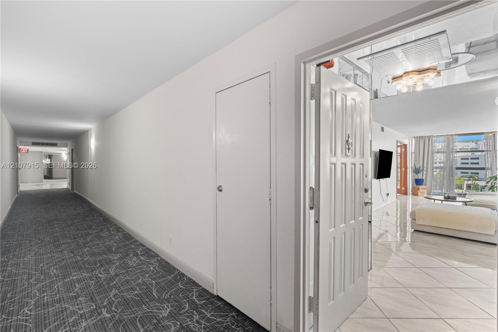 Entryway featuring a solid panel door, patterned wall-to-wall carpeting, and light-colored tile flooring Entryway featuring a solid panel door, patterned wall-to-wall carpeting, and light-colored tile flooring