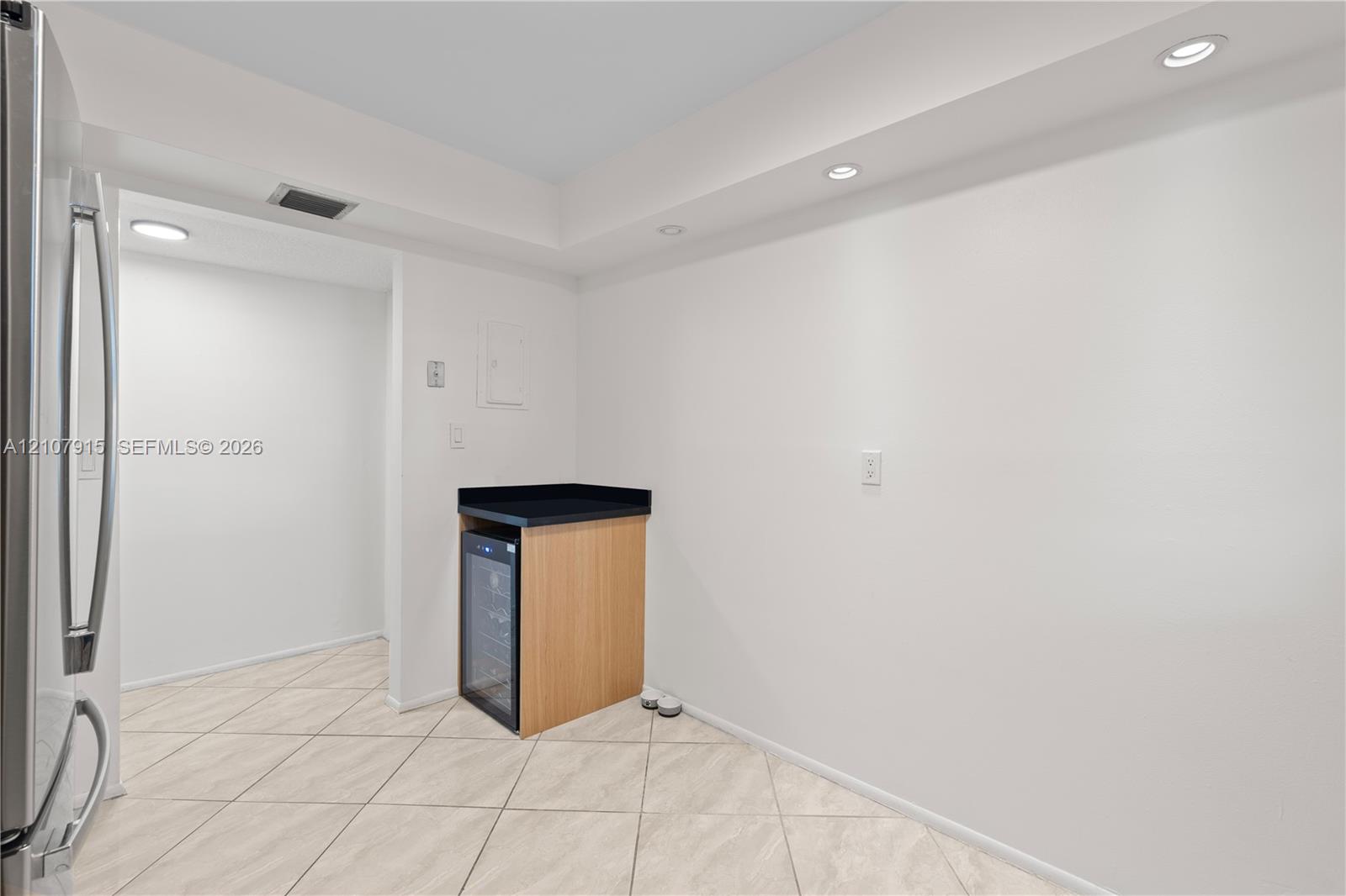 Built-in cabinetry with a stone countertop, integrated wine cooler, recessed lighting, and tile flooring