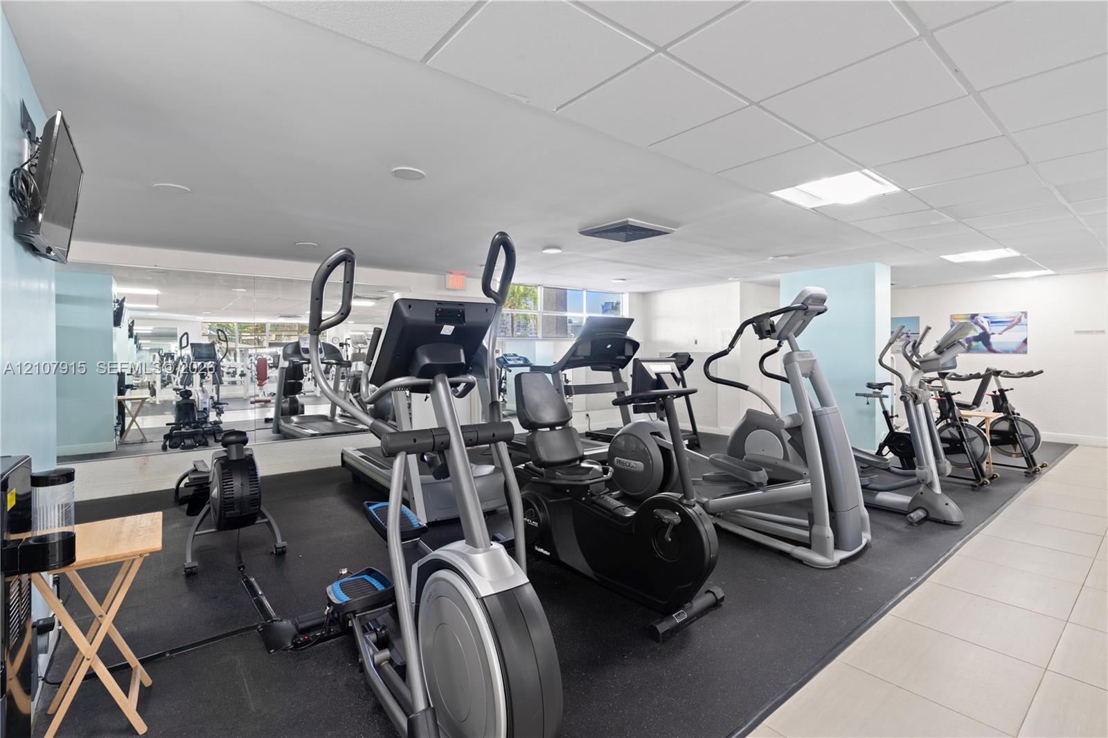 Fitness center featuring rubberized flooring, expansive wall-to-wall mirrors, recessed lighting, and large windows