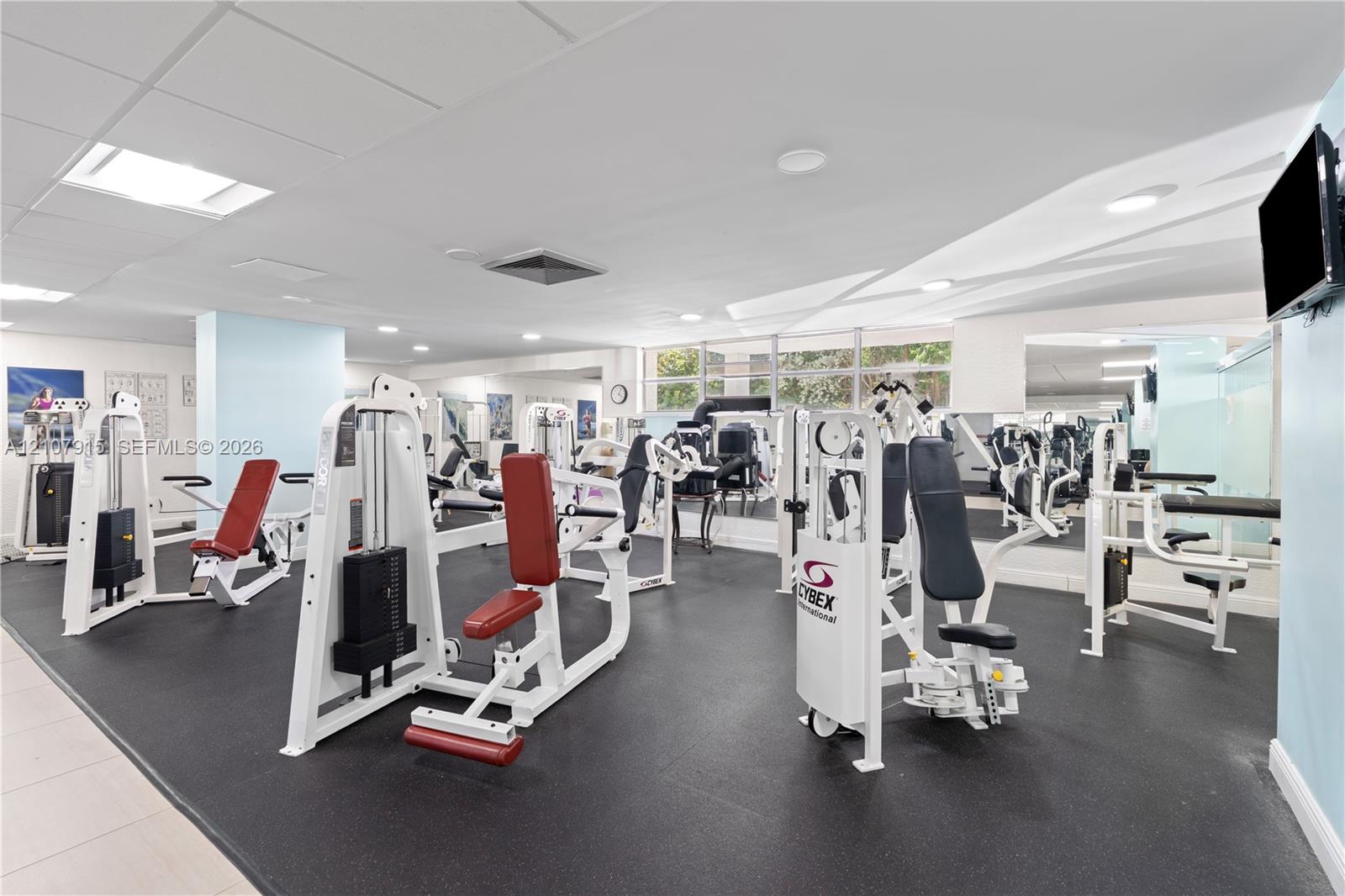 Fitness center featuring recessed lighting, wall-to-wall mirrors, and durable rubber flooring