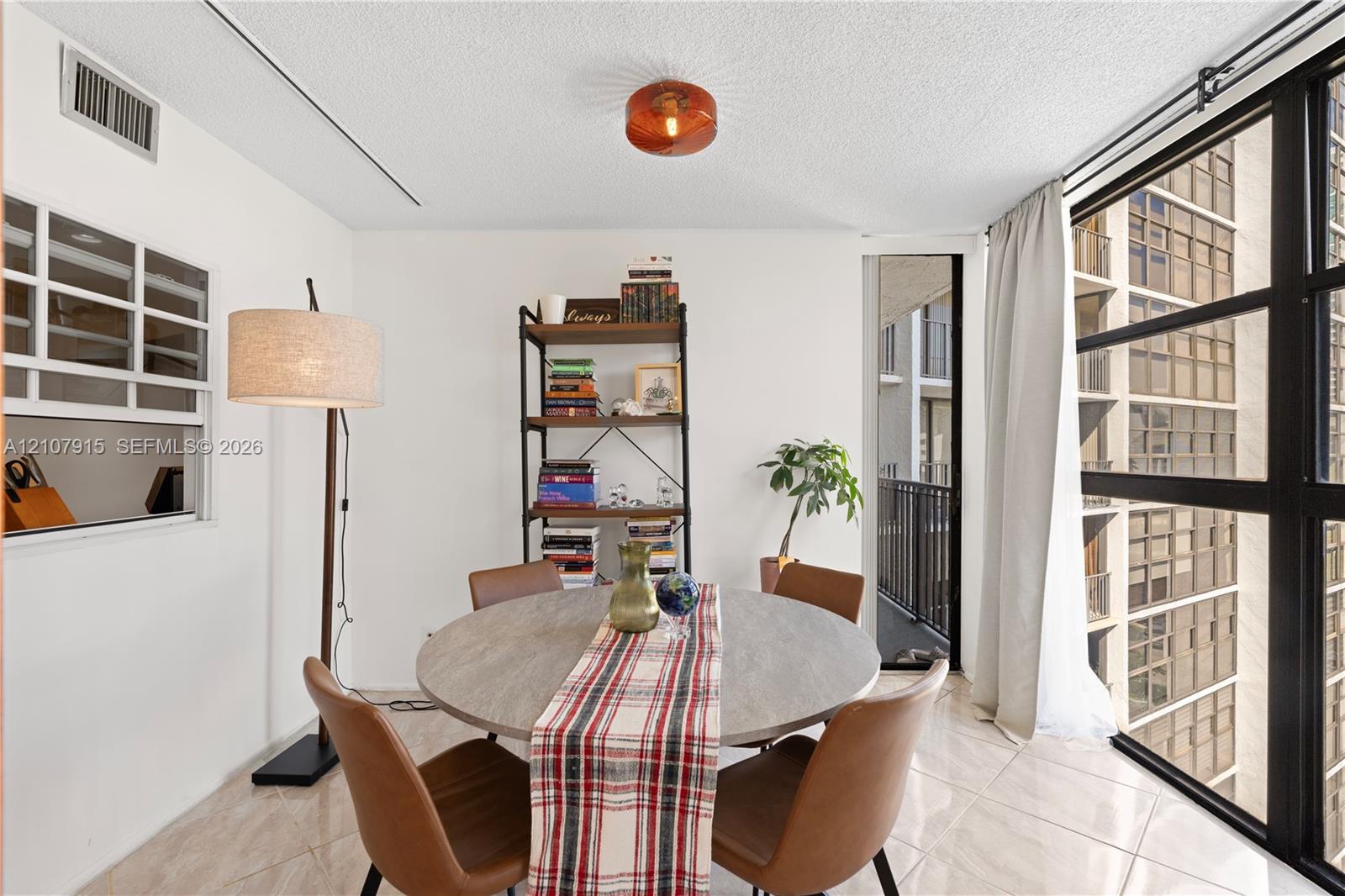 Large floor-to-ceiling windows with black metal frames, polished tile flooring, glass-paneled interior window, and flush-mount industrial-style lighting fixture