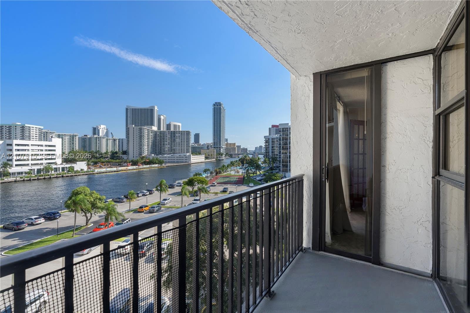 Private balcony featuring metal railings and concrete flooring with urban water scenery