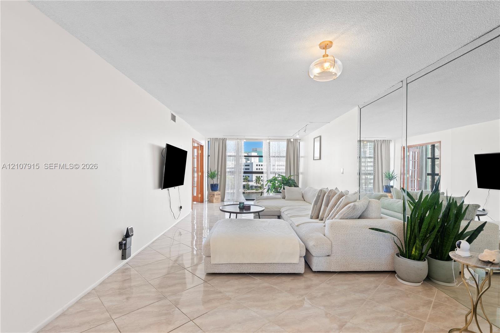 Floor-to-ceiling mirrored wall, polished tile flooring, glass-paneled entry door, and floor-to-ceiling windows with balcony access Floor-to-ceiling mirrored wall, polished tile flooring, glass-paneled entry door, and floor-to-ceiling windows with balcony access