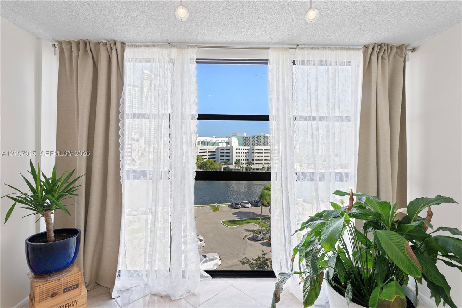 Floor-to-ceiling windows with black framing, tile flooring, and dual overhead recessed lighting