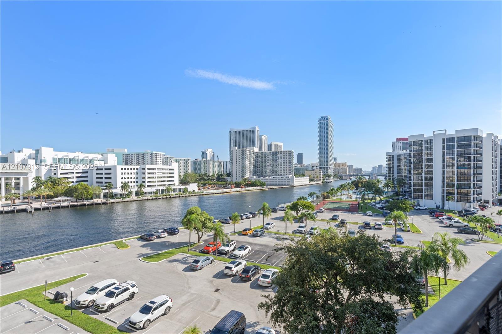 Elevated perspective featuring a waterfront urban landscape, deep-water canal, mature palm trees, and asphalt surface parking