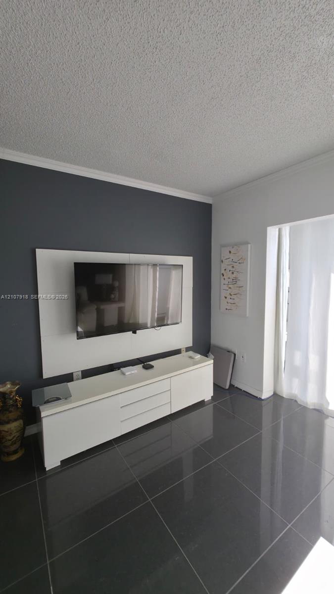 Large-format gray tile flooring, accent wall with built-in white media console, and white crown molding Large-format gray tile flooring, accent wall with built-in white media console, and white crown molding