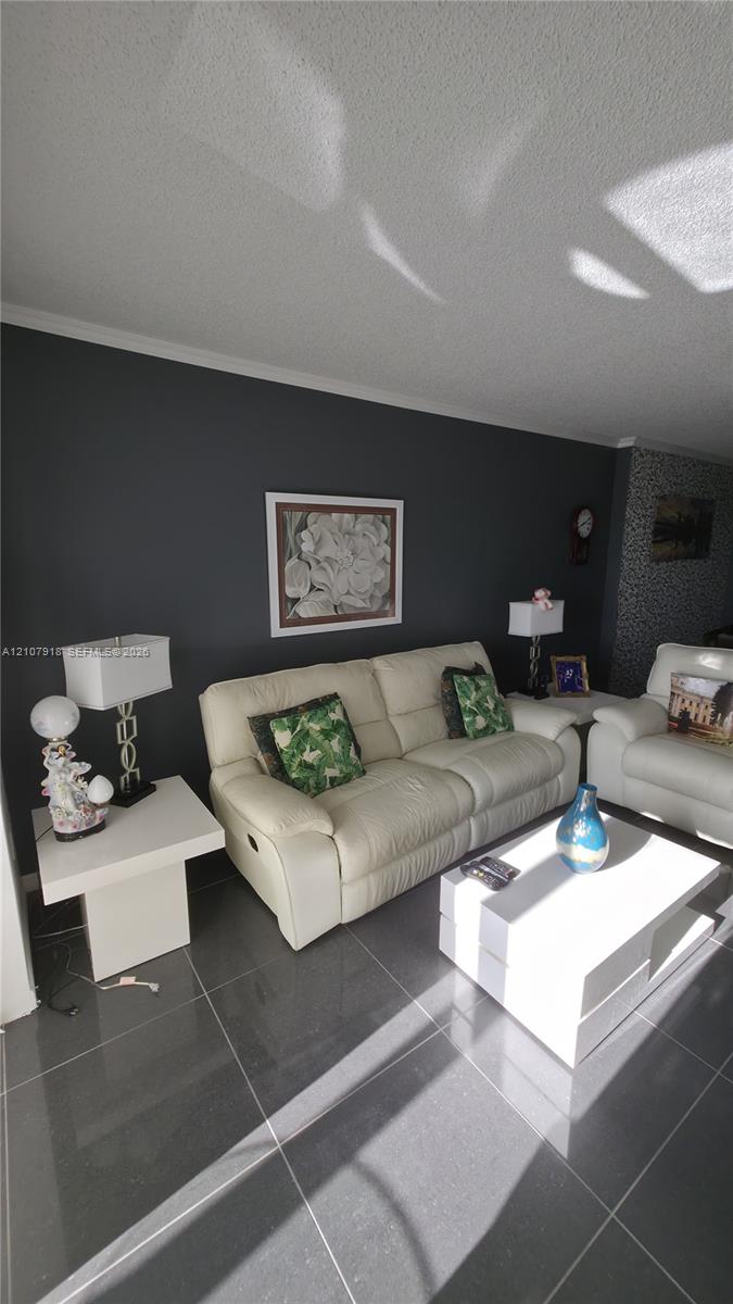 Living area featuring dark-toned stone-finish tile flooring and a charcoal accent wall Living area featuring dark-toned stone-finish tile flooring and a charcoal accent wall