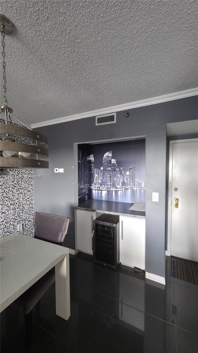 Built-in wet bar featuring dark cabinetry, countertop, and integrated wine cooler, complemented by high-gloss floor tile and a contemporary multi-tier drum pendant light