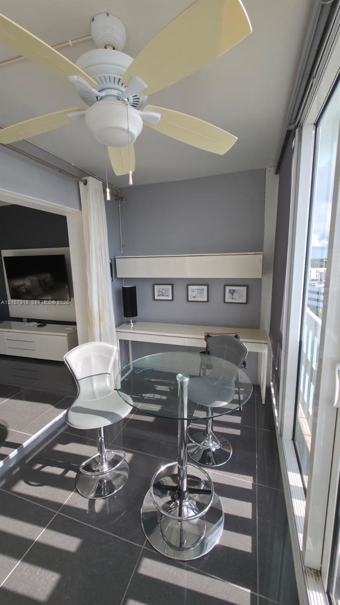 Large-format floor tile, built-in wall-mounted desk with overhead cabinetry, and multi-blade ceiling fan