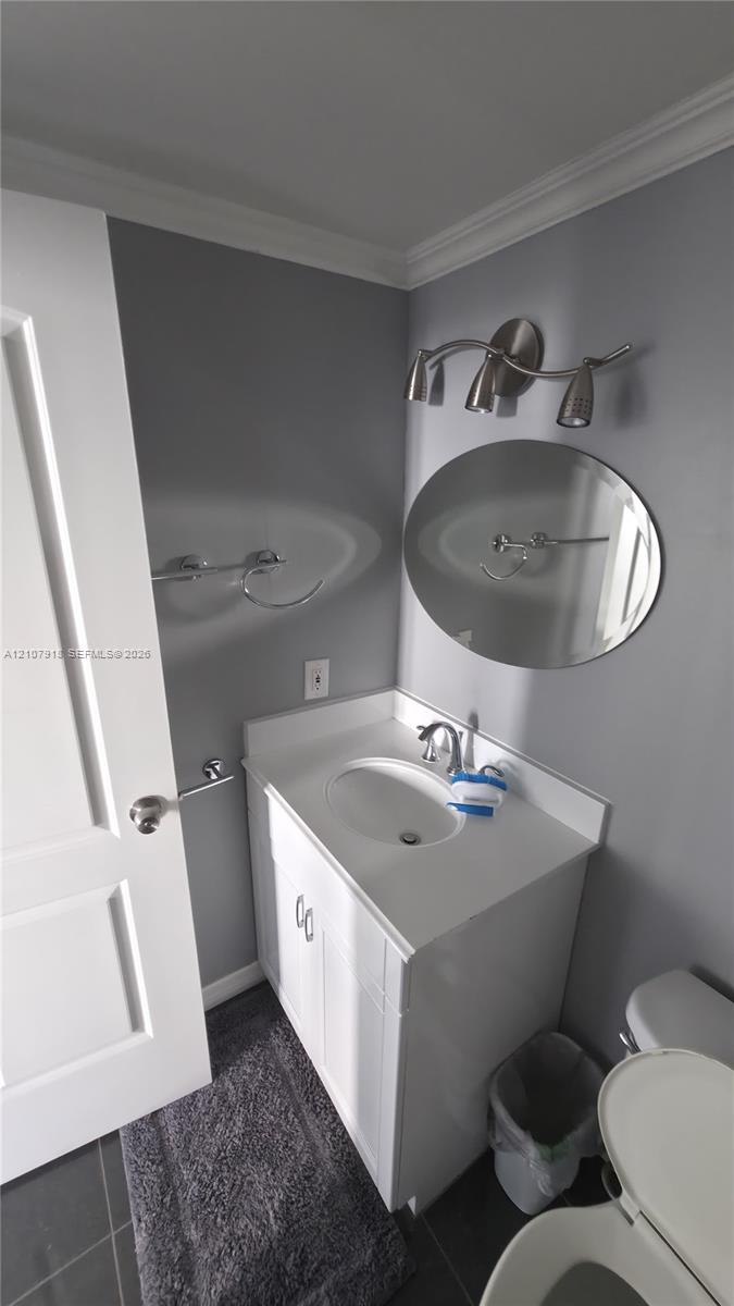 White vanity with an integrated countertop and basin, oval frameless mirror, and brushed-finish three-light vanity fixture
