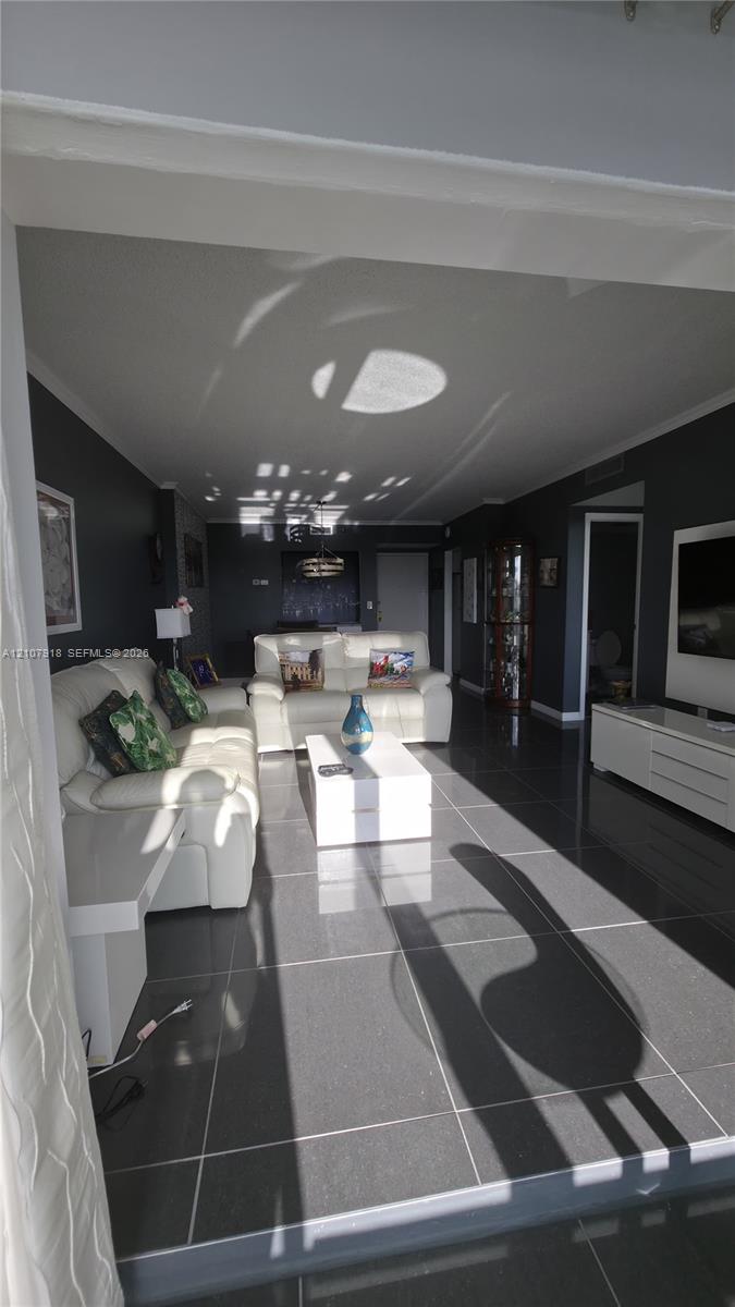 Open-concept living space featuring large-format dark floor tiles and deep-toned wall finishes Open-concept living space featuring large-format dark floor tiles and deep-toned wall finishes