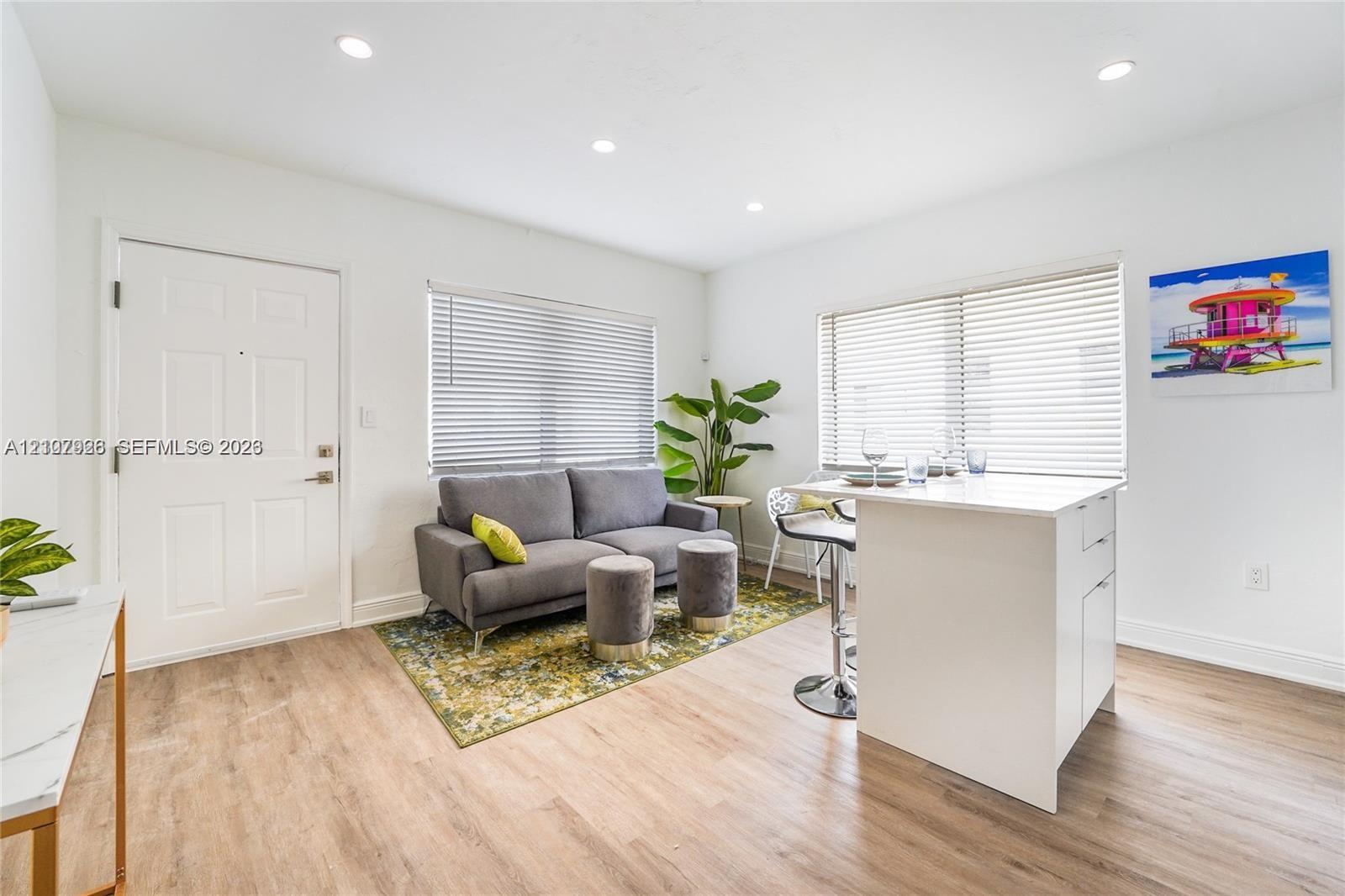 Interior featuring wood-finish flooring, recessed lighting, and a white kitchen island with solid surface countertop