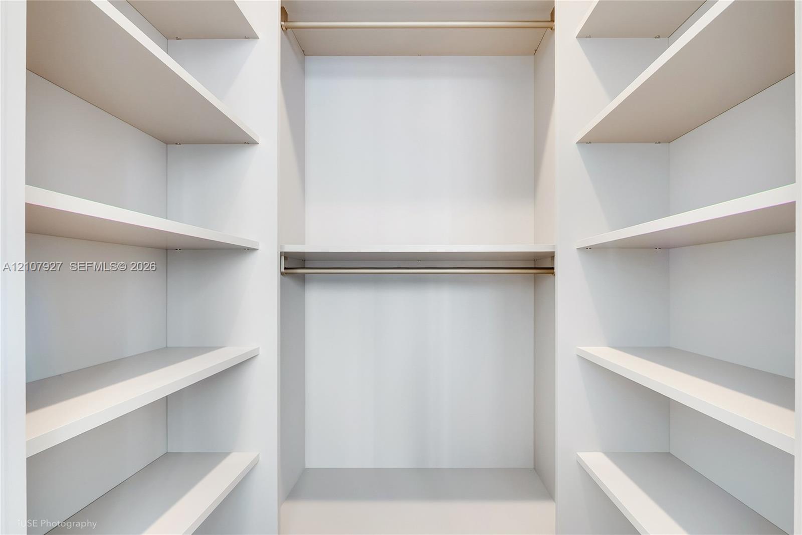 Custom closet featuring white built-in shelving and dual horizontal metal hanging rods