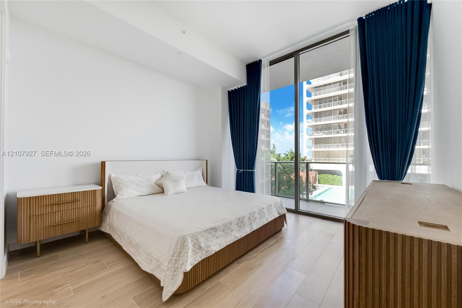 Floor-to-ceiling windows featuring access to a private balcony, wood-finish flooring, and neutral wall tones Floor-to-ceiling windows featuring access to a private balcony, wood-finish flooring, and neutral wall tones