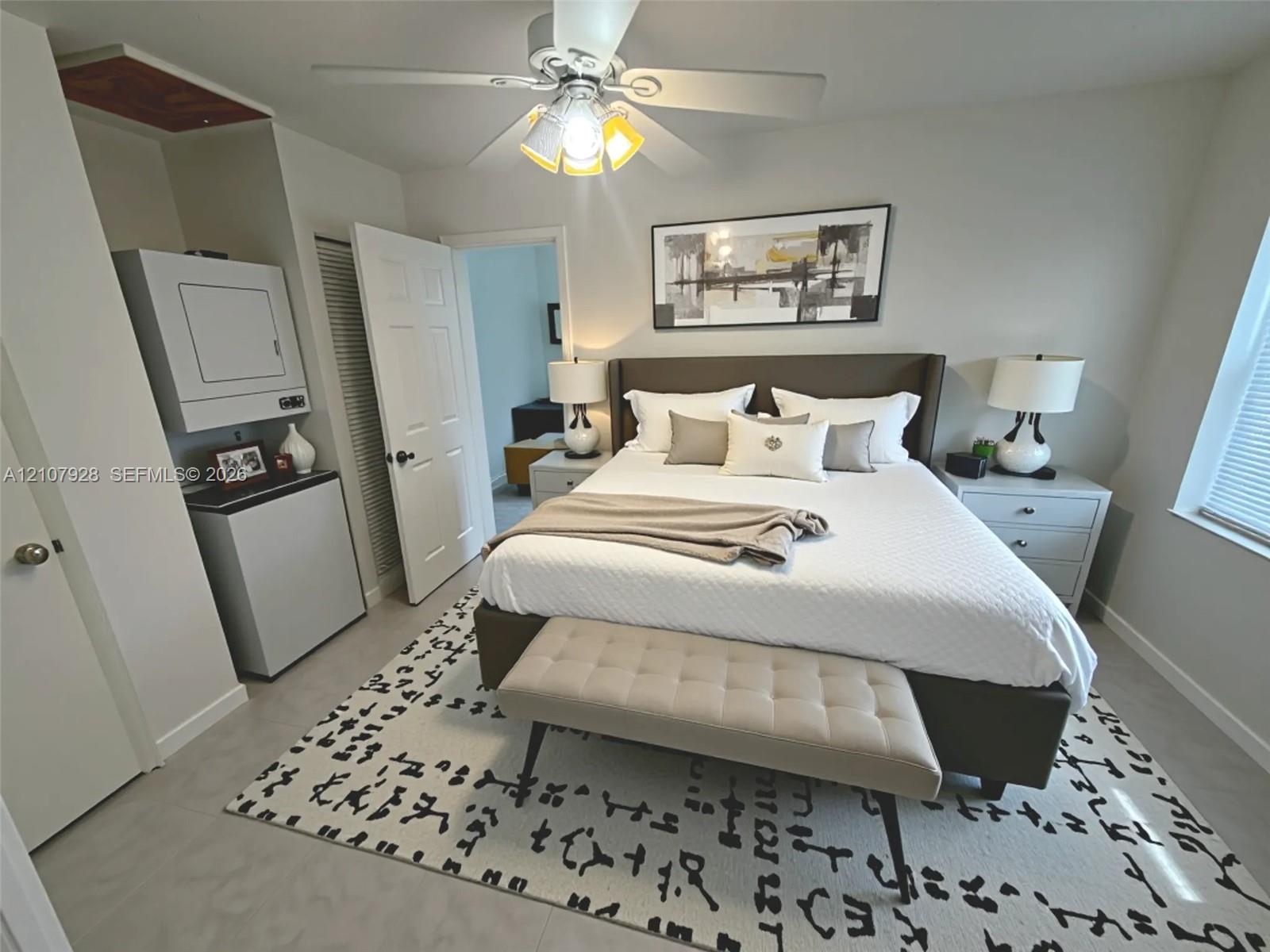 Interior room featuring smooth-finish tile flooring, a ceiling fan with integrated lighting, and a built-in wall-mounted laundry appliance setup