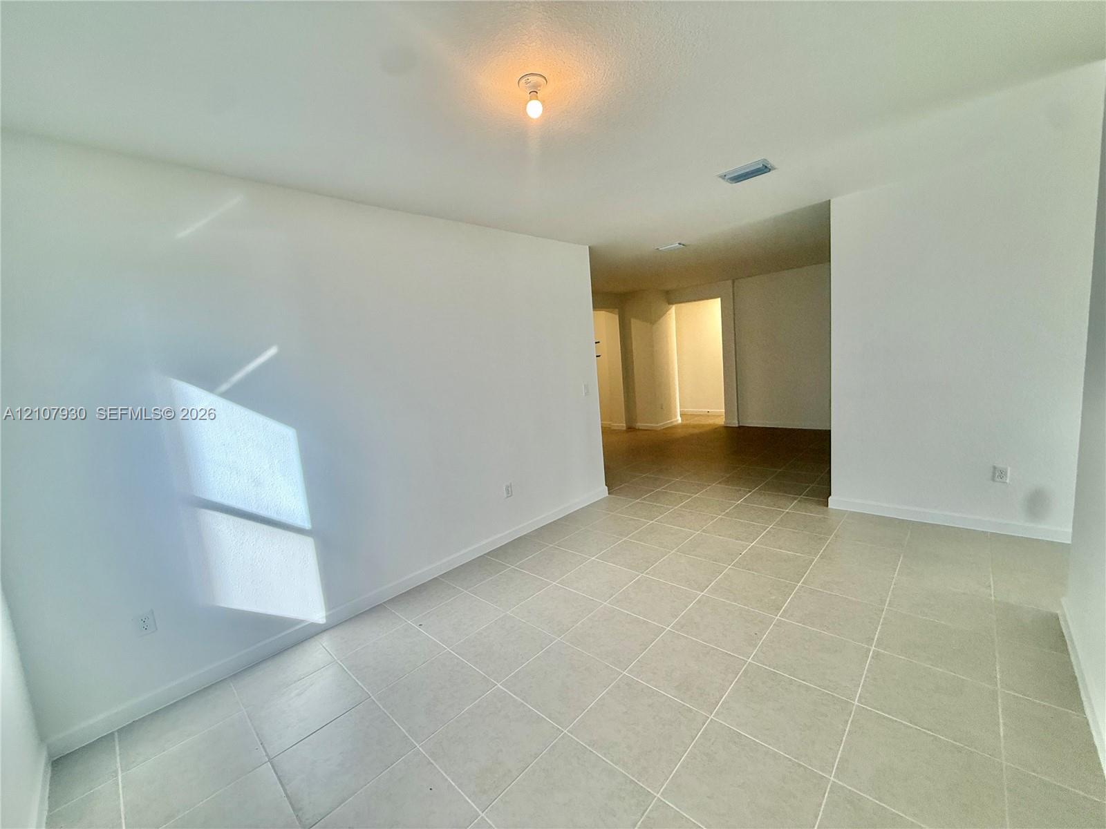 Open interior space featuring neutral wall paint, large-format tile flooring, and a flush-mount ceiling light fixture