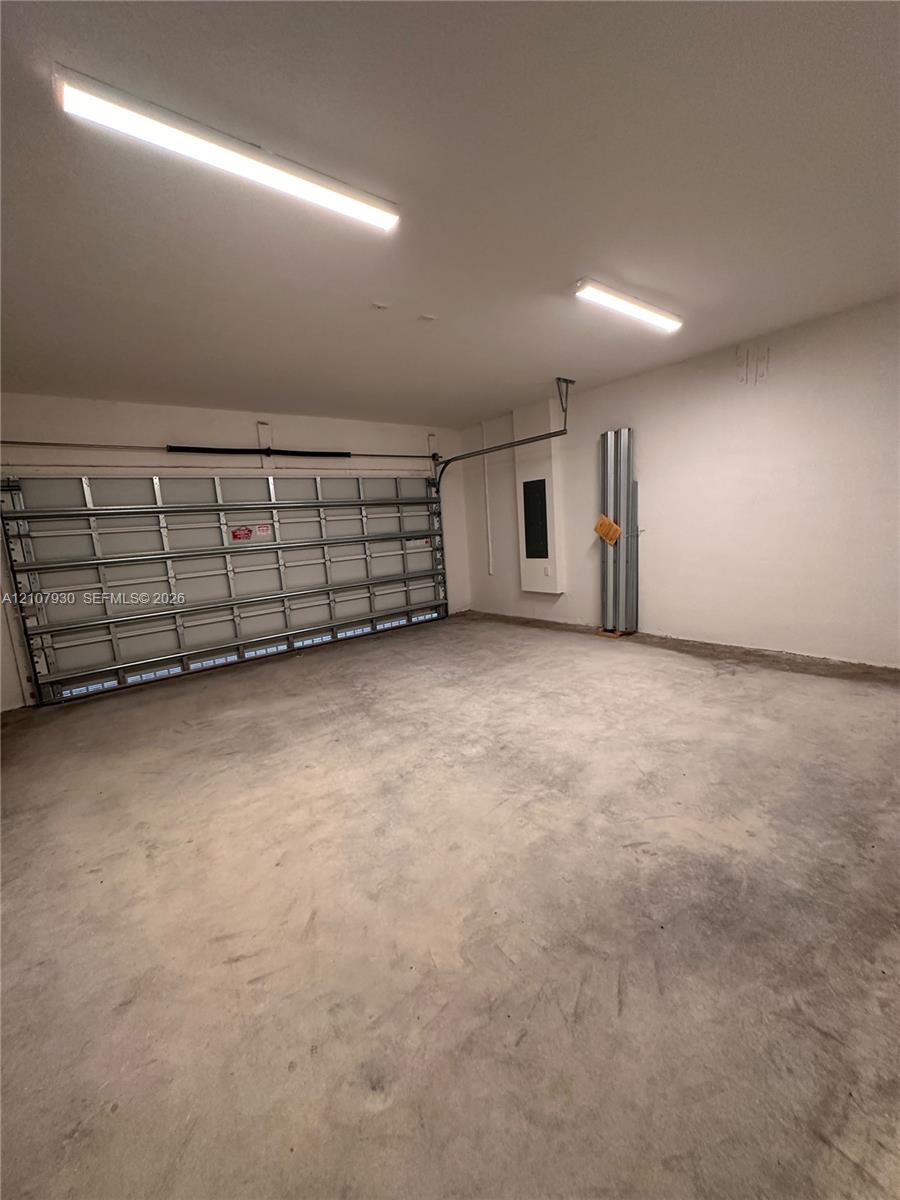 Enclosed two-car garage featuring a sectional metal door, concrete flooring, and linear fluorescent overhead lighting