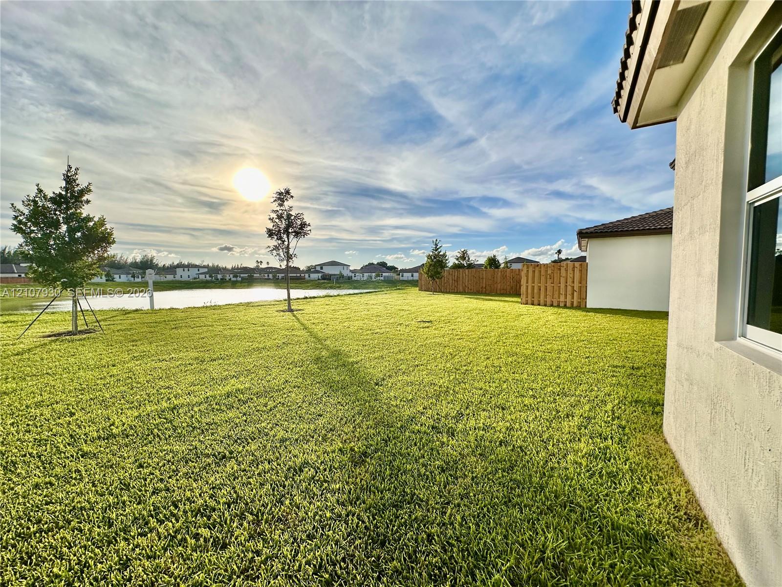 Backyard featuring a manicured lawn, water frontage, and wood privacy fencing Backyard featuring a manicured lawn, water frontage, and wood privacy fencing