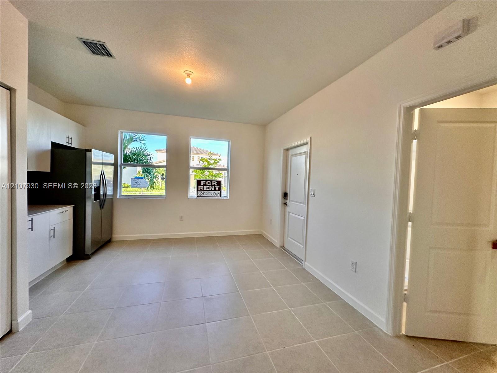 Kitchen featuring matte white cabinetry, stainless steel side-by-side refrigerator, neutral ceramic tile flooring, and dual picture windows