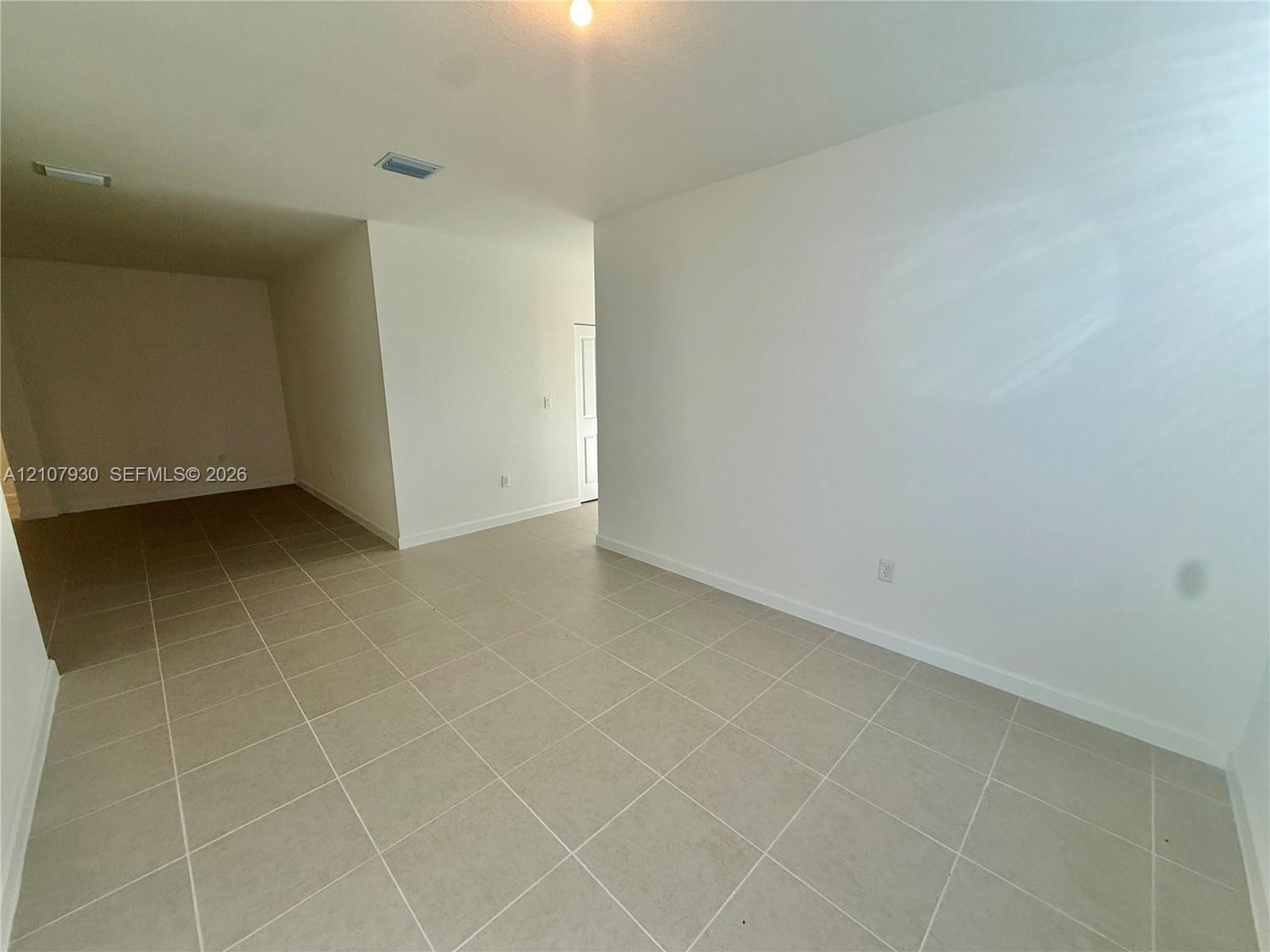 Interior space featuring neutral wall-to-wall tile flooring and crisp white walls