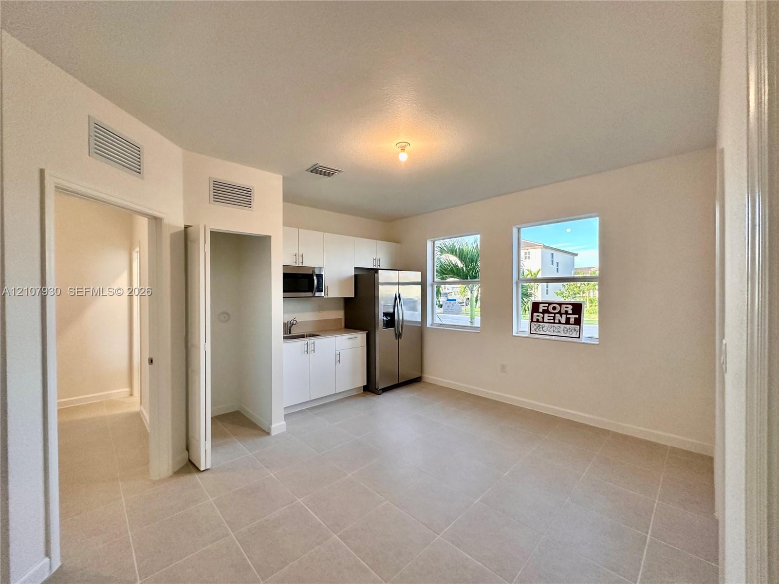 Kitchen featuring white cabinetry, stainless steel appliances, neutral tile flooring, and dual windows