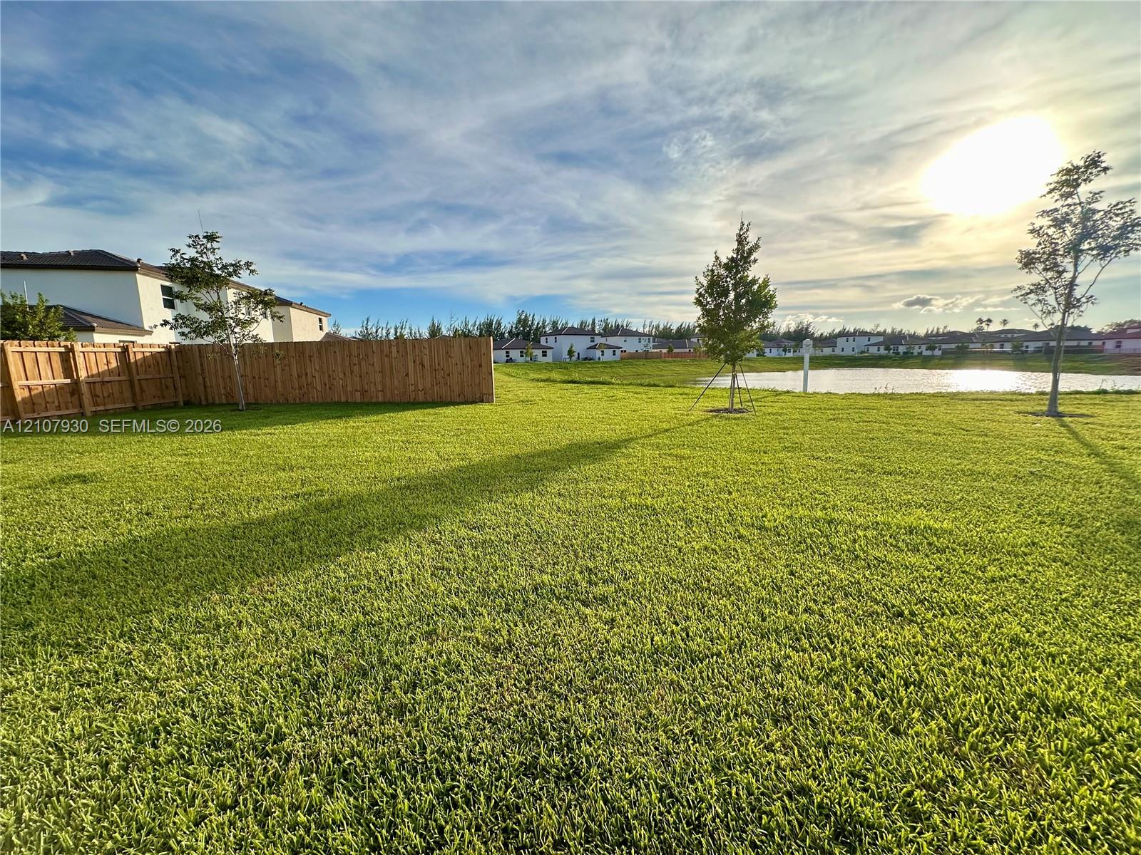 Expansive backyard featuring a large grass lawn, perimeter wood fencing, and waterfront property boundaries Expansive backyard featuring a large grass lawn, perimeter wood fencing, and waterfront property boundaries