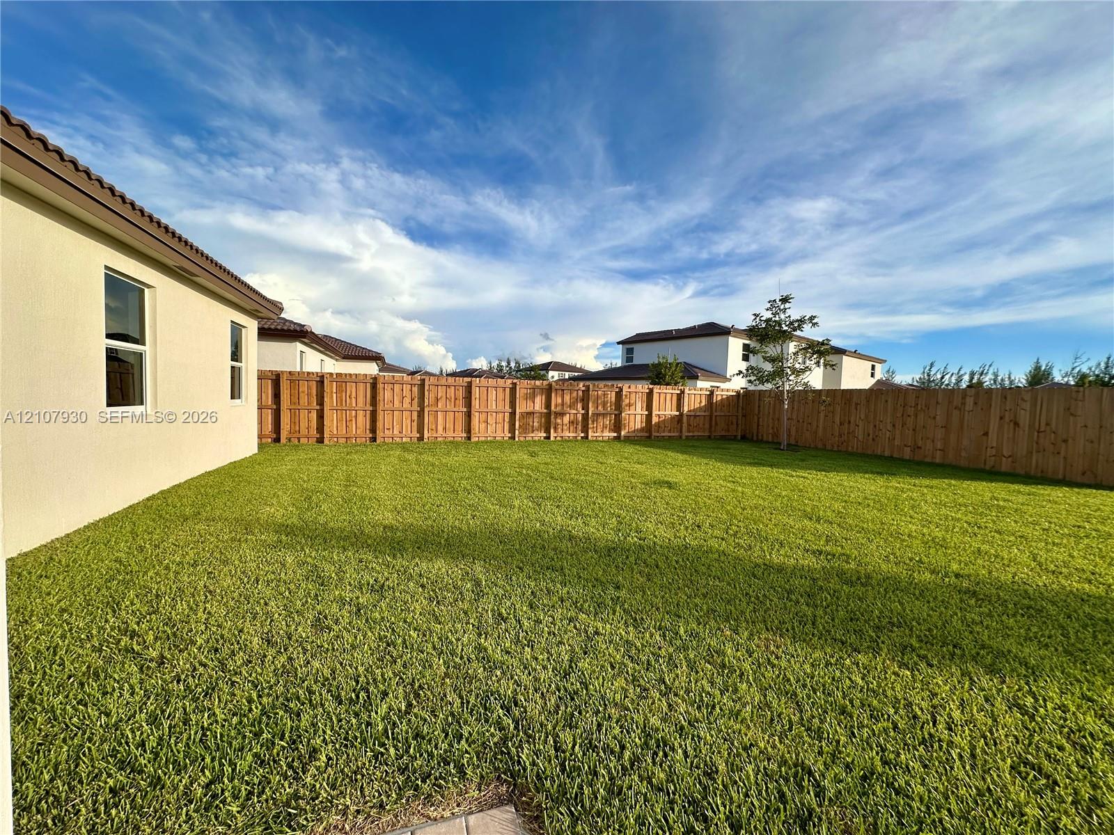 Expansive backyard featuring a level lawn and a wood privacy fence Expansive backyard featuring a level lawn and a wood privacy fence