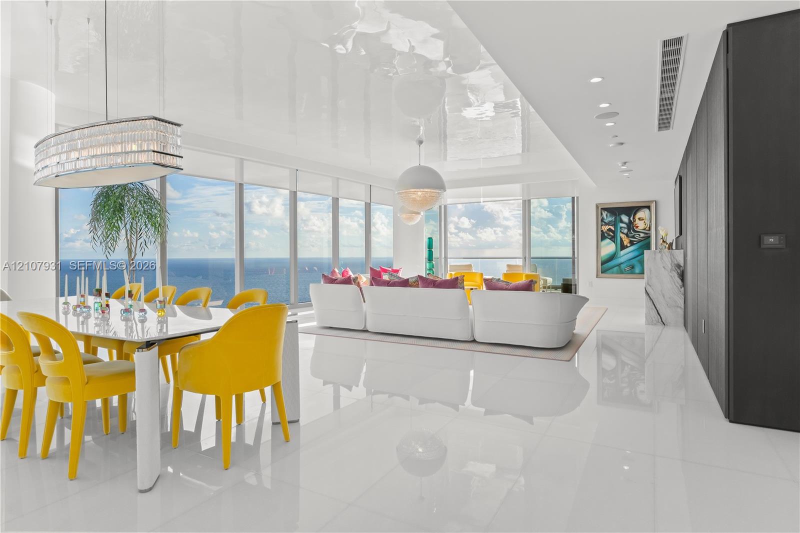Open-concept interior featuring high-gloss flooring, floor-to-ceiling windows, panoramic ocean scenery, recessed lighting, and a crystal-accented chandelier