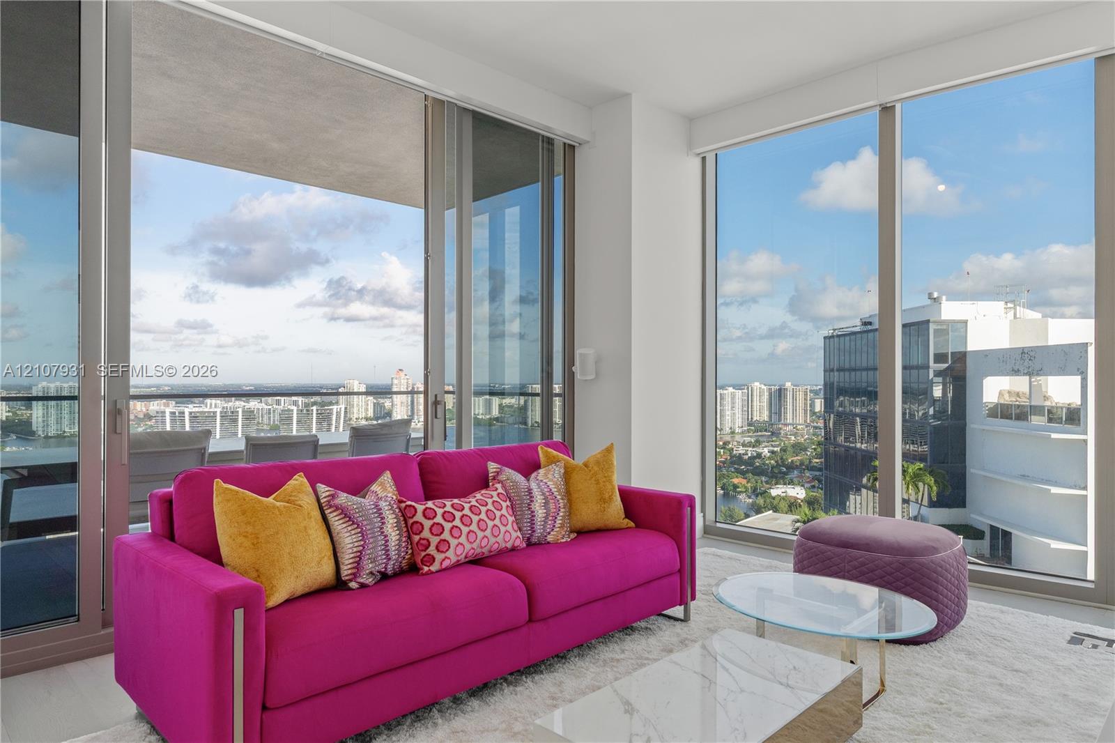 Floor-to-ceiling glass windows, sliding glass doors, and a covered balcony