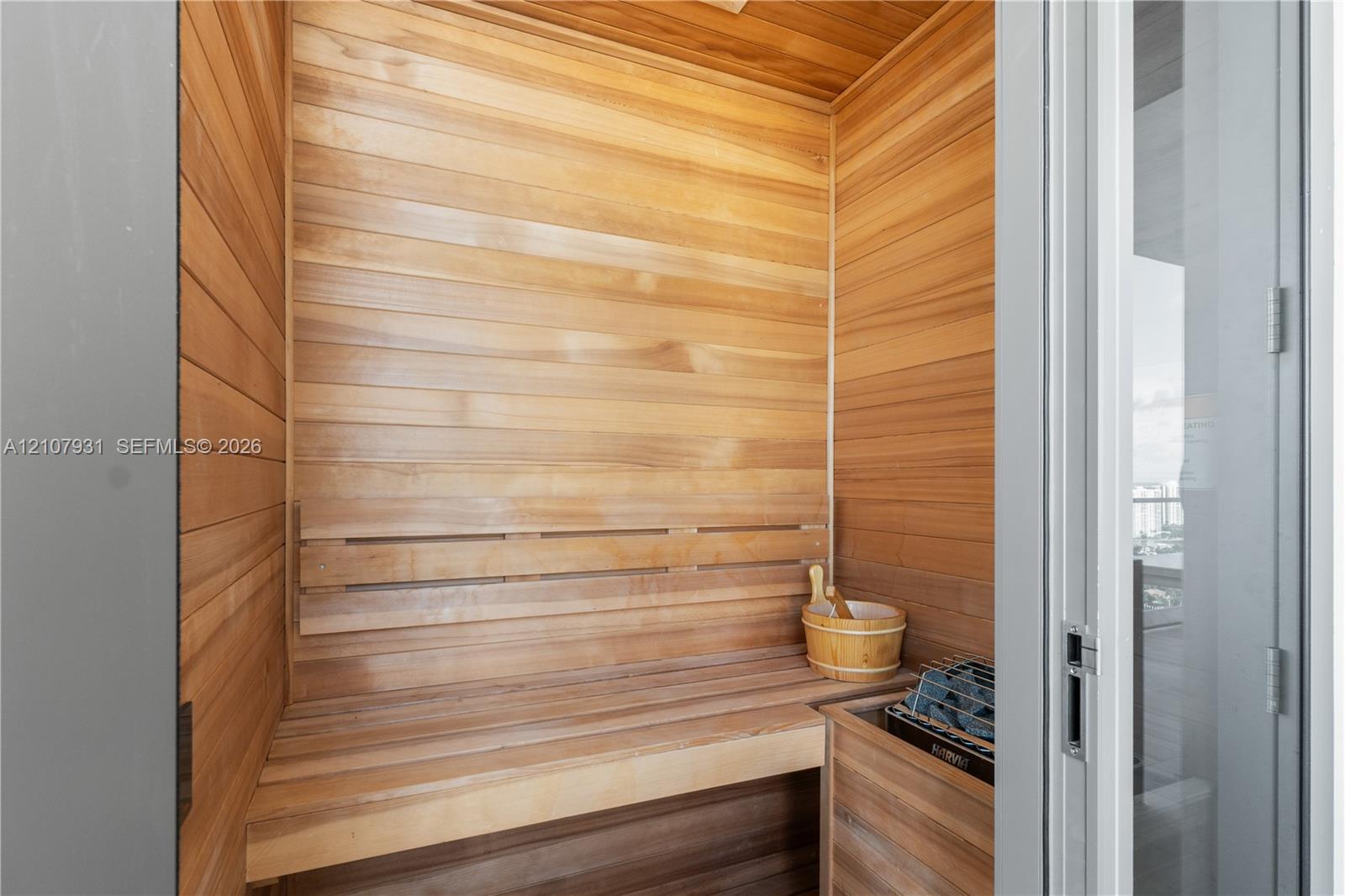Custom sauna featuring natural wood wall paneling, tiered wood-finish bench seating, and an integrated heating element