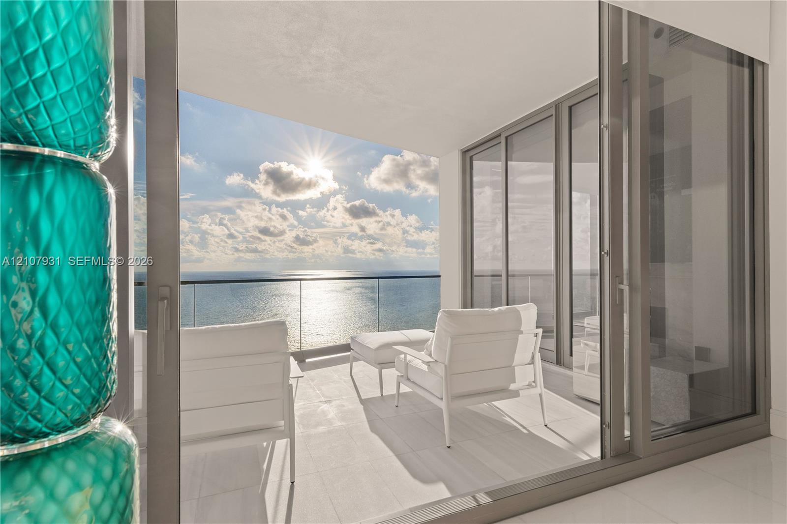 Covered balcony featuring large-format tile flooring, frameless glass railing, and floor-to-ceiling sliding glass doors