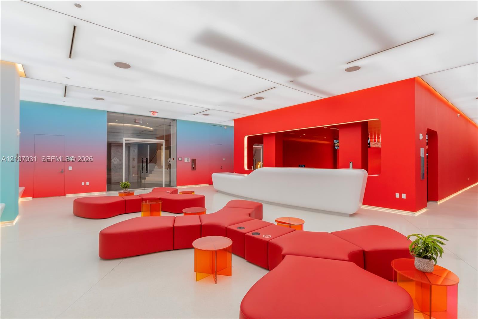 Contemporary lobby featuring a sculpted white built-in reception desk, high-gloss solid flooring, recessed linear lighting, and gradient-finished walls