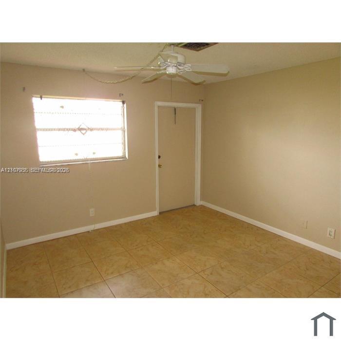 Interior space featuring tile flooring, a window with security bars, and a ceiling fan with integrated lighting